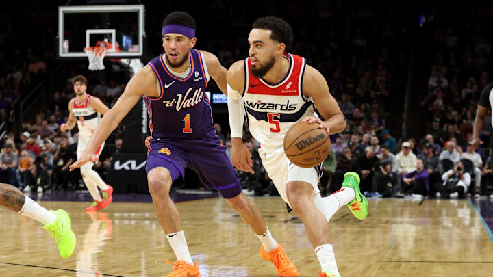 Dec 17, 2023; Phoenix, Arizona, USA; Washington Wizards guard Tyus Jones (5) drives to the net against Phoenix Suns guard Devin Booker (1) during the first quarter at Footprint Center. Mandatory Credit: Zachary BonDurant-Imagn Images