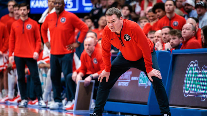 Mar 8, 2025; Lawrence, Kansas, USA; Arizona Wildcats coach Tommy Lloyd watches game play during the second half against the Kansas Jayhawks at Allen Fieldhouse. Mandatory Credit: William Purnell-Imagn Images