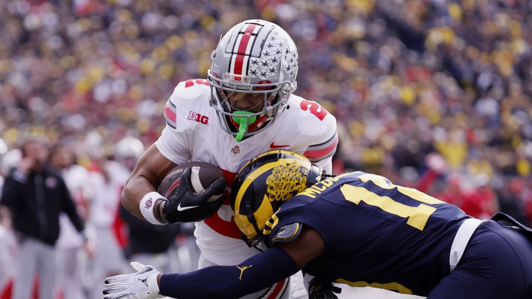 Nov 25, 2023; Ann Arbor, Michigan, USA; Ohio State Buckeyes wide receiver Emeka Egbuka (2) is hit by Michigan Wolverines defensive back Ja'Den McBurrows (18) as he scores a touchdown in the first half against the Michigan Wolverines at Michigan Stadium. Mandatory Credit: Rick Osentoski-USA TODAY Sports