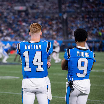 Aug 8, 2025; Charlotte, North Carolina, USA; Carolina Panthers quarterback Andy Dalton (14) and quarterback Bryce Young (9) watch from the sidelines during the fourth quarter at Bank of America Stadium. 