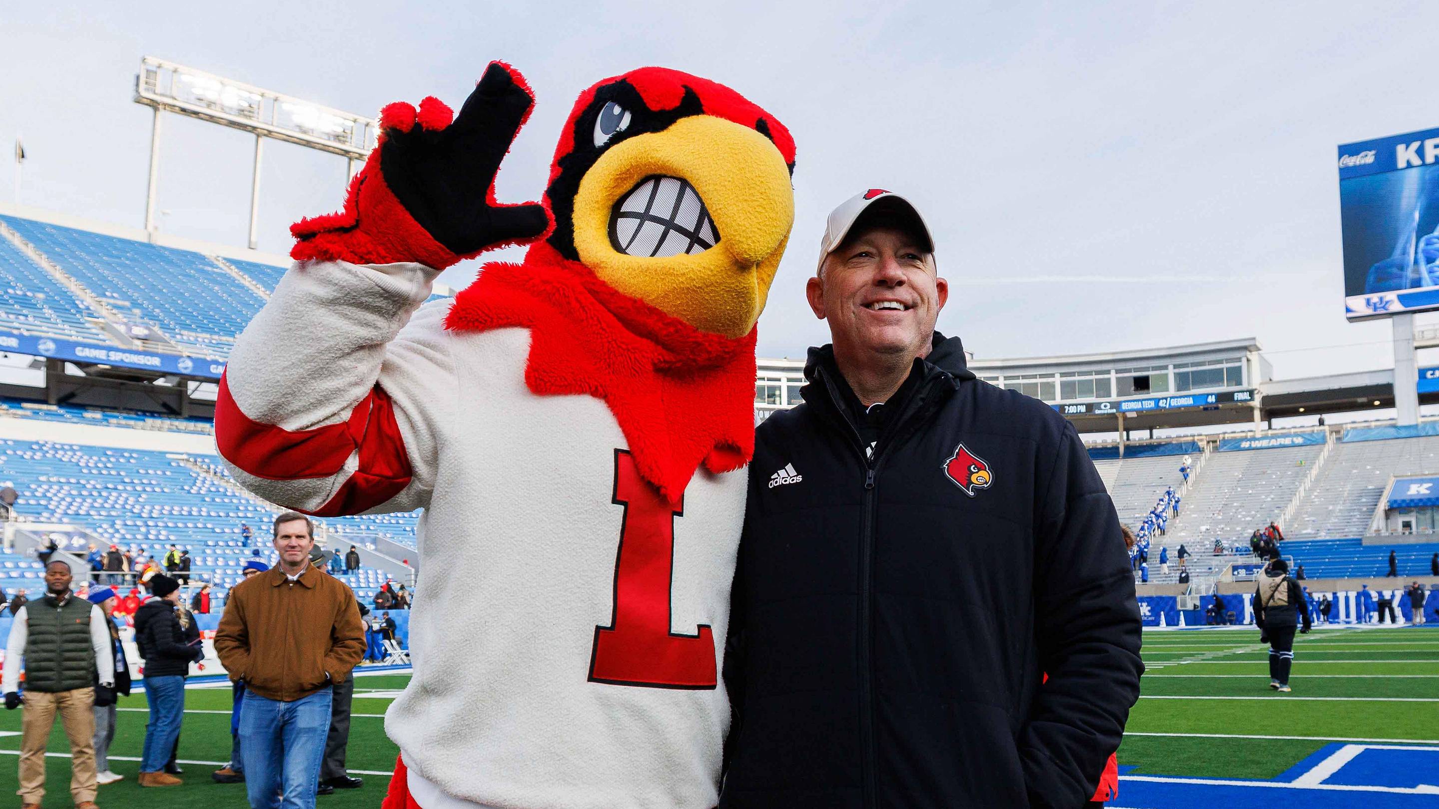 Nov 30, 2024; Lexington, Kentucky, USA; Louisville Cardinals head coach Jeff Brohm poses for a photo with the Cardinal mascot after the game against the Kentucky Wildcats at Kroger Field. Mandatory Credit: Jordan Prather-Imagn Images