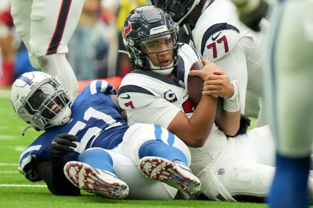 Football player Kwity Paye sacks C.J. Stroud in a blue jersey.