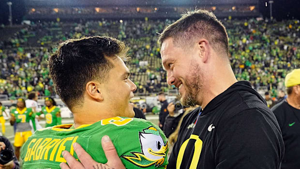 Oregon quarterback Dillon Gabriel, left, and coach Dan Lanning embrace after defeating Maryland at Autzen Stadium.