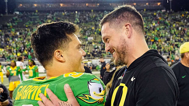 Oregon quarterback Dillon Gabriel, left, and coach Dan Lanning embrace after defeating Maryland at Autzen Stadium.