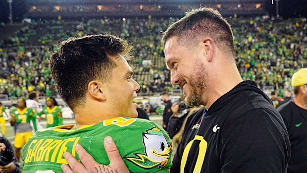 Oregon quarterback Dillon Gabriel, left, and coach Dan Lanning embrace after defeating Maryland at Autzen Stadium.