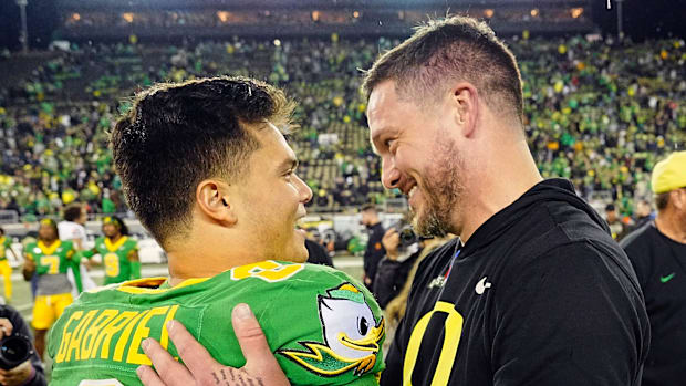 Oregon quarterback Dillon Gabriel, left, and coach Dan Lanning embrace after defeating Maryland at Autzen Stadium
