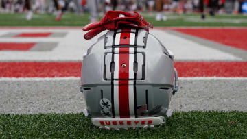 An Ohio State football helmet next to the field at Ohio State while Buckeyes football players warm