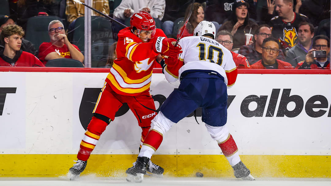 Mar 20, 2026; Calgary, Alberta, CAN; Calgary Flames defenseman Zayne Parekh (19) and Florida Panthers left wing A.J. Greer (10) battle for the puck during the third period at Scotiabank Saddledome. Mandatory Credit: Sergei Belski-Imagn Images