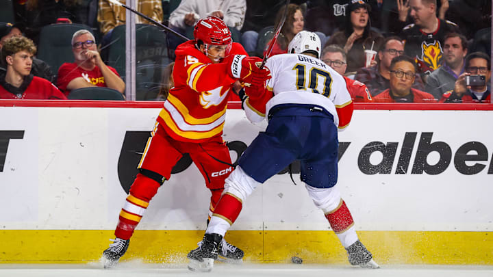Mar 20, 2026; Calgary, Alberta, CAN; Calgary Flames defenseman Zayne Parekh (19) and Florida Panthers left wing A.J. Greer (10) battle for the puck during the third period at Scotiabank Saddledome. Mandatory Credit: Sergei Belski-Imagn Images
