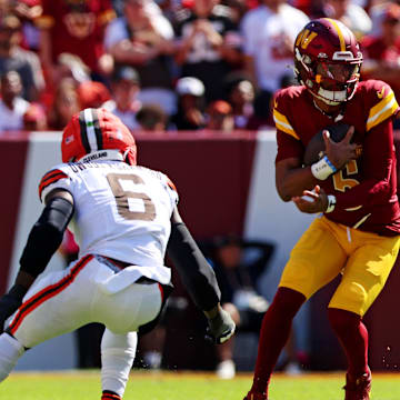 Oct 6, 2024; Landover, Maryland, USA; Washington Commanders quarterback Jayden Daniels (5) runs the ball against Cleveland Browns linebacker Jeremiah Owusu-Koramoah (6) during the first quarter at NorthWest Stadium. Mandatory Credit: Peter Casey-Imagn Images