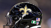 Sep 7, 2025; New Orleans, Louisiana, USA;  Detailed view of the helmet worn by New Orleans Saints safety Ugo Amadi (0) with and American Flag and the flag of Nigeria during warmups against the Arizona Cardinals at Caesars Superdome. Mandatory Credit: Stephen Lew-Imagn Images