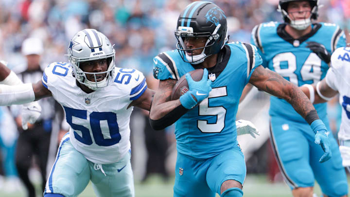 Oct 12, 2025; Charlotte, North Carolina, USA; Carolina Panthers running back Rico Dowdle (5) runs with the ball while getting pressured by Dallas Cowboys linebacker Shemar James (50) during the second half at Bank of America Stadium.