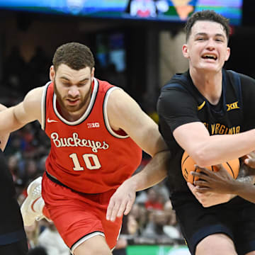 Dec 30, 2023; Cleveland, Ohio, USA; West Virginia Mountaineers forward Quinn Slazinski (11) drives to the basket against Ohio State Buckeyes guard Dale Bonner (4) and forward Jamison Battle (10) during the second half at Rocket Mortgage FieldHouse. Mandatory Credit: Ken Blaze-Imagn Images