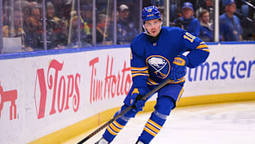 Henri Jokiharju (10) with the puck along the boards in a game against the Boston Bruins.