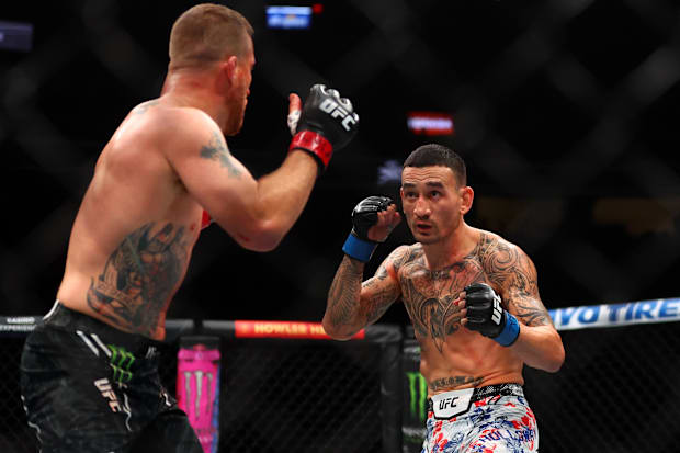 Max Holloway (blue gloves) fights Justin Gaethje (red gloves) during UFC 300 at T-Mobile Arena. 