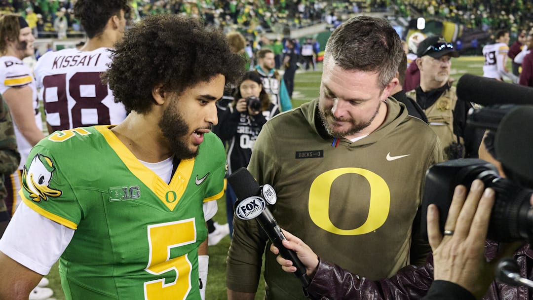 Nov 14, 2025; Eugene, Oregon, USA; Oregon Ducks quarterback Dante Moore (5) and head coach Dan Lanning talk talk to a reporter after a game against the Minnesota Golden Gophers at Autzen Stadium. Mandatory Credit: Troy Wayrynen-Imagn Images