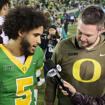 Nov 14, 2025; Eugene, Oregon, USA; Oregon Ducks quarterback Dante Moore (5) and head coach Dan Lanning talk talk to a reporter after a game against the Minnesota Golden Gophers at Autzen Stadium. Mandatory Credit: Troy Wayrynen-Imagn Images