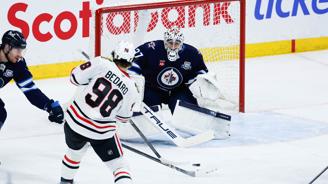 Mar 3, 2026; Winnipeg, Manitoba, CAN;  Winnipeg Jets goalie Connor Hellebuyck (37) makes a save against Chicago Blackhawks forward Connor Bedard (98) during the second period at Canada Life Centre. Mandatory Credit: Terrence Lee-Imagn Images