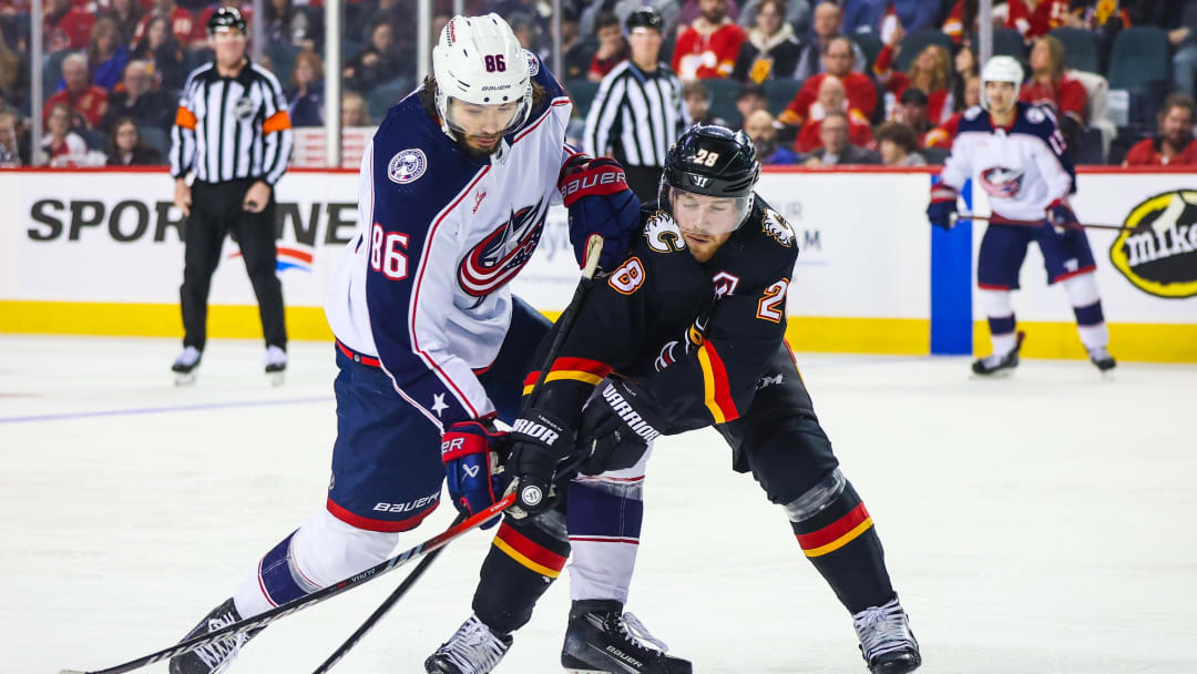 Jan 25, 2024; Calgary, Alberta, CAN; Columbus Blue Jackets right wing Kirill Marchenko (86) and Calgary Flames center Elias Lindholm (28) battles for the puck during the second period at Scotiabank Saddledome. Mandatory Credit: Sergei Belski-USA TODAY Sports