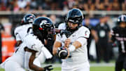 Sep 28, 2024; Lubbock, Texas, USA;  Cincinnati Bearcats quarterback Brandan Sorsby (2) hands the ball in the first half to running back Coey Kiner (21) during the game against the Texas Tech Red Raiders at Jones AT&T Stadium and Cody Campbell Field. Mandatory Credit: Michael C. Johnson-Imagn Images