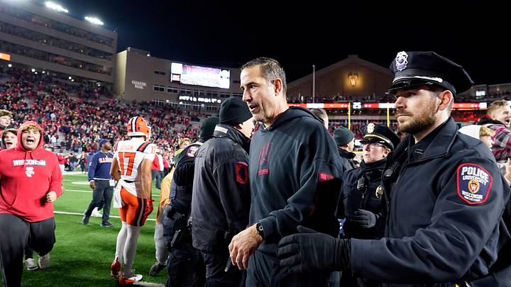 Nov 22, 2025; Madison, Wisconsin, USA; Wisconsin Badgers head coach Luke Fickell is escorted off the field as fans storm the field following a 27-10 win over the Illinois Fighting Illini at Camp Randall Stadium. Mandatory Credit: Kayla Wolf-Imagn Images