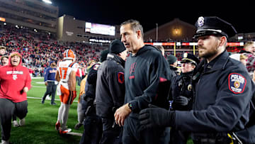 Nov 22, 2025; Madison, Wisconsin, USA; Wisconsin Badgers head coach Luke Fickell is escorted off the field as fans storm the field following a 27-10 win over the Illinois Fighting Illini at Camp Randall Stadium. Mandatory Credit: Kayla Wolf-Imagn Images