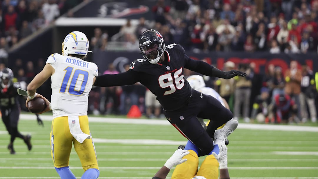 Jan 11, 2025; Houston, Texas, USA;  Los Angeles Chargers quarterback Justin Herbert (10) is defended by Houston Texans defensive end Denico Autry (96) in the second quarter in an AFC wild card game at NRG Stadium. Mandatory Credit: Thomas Shea-Imagn Images