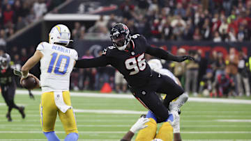 Jan 11, 2025; Houston, Texas, USA;  Los Angeles Chargers quarterback Justin Herbert (10) is defended by Houston Texans defensive end Denico Autry (96) in the second quarter in an AFC wild card game at NRG Stadium. Mandatory Credit: Thomas Shea-Imagn Images