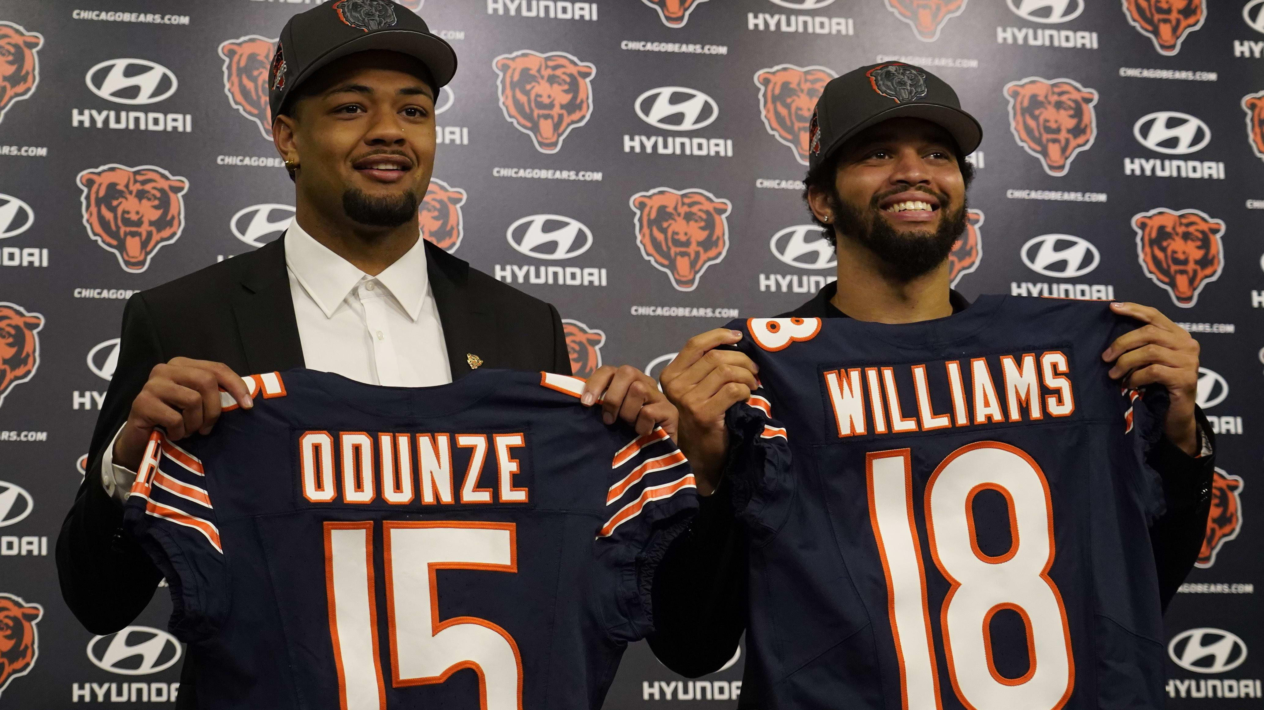 Rome Odunze holds up his 15 jersey and Caleb Williams his 18 at their first Halas Hall press conference.