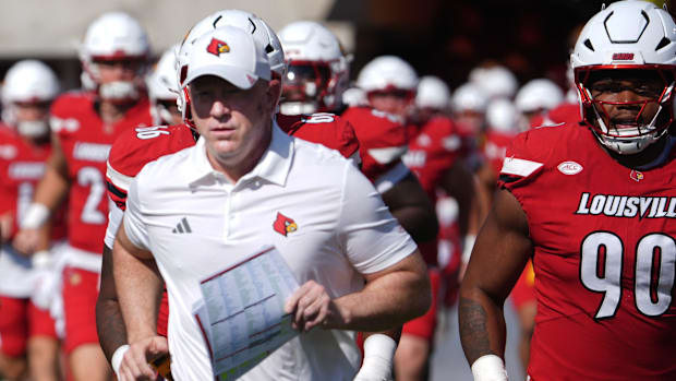 Louisville coach Jeff Brohm brings his team out onto the field.