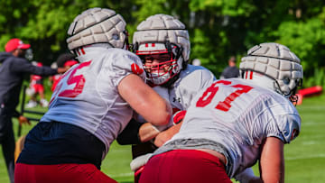 Offensive lineman Joe Brunner, center, takes on Kevin Heywood (55) and JP Benzschawel (67) during football practice Wednesday. 