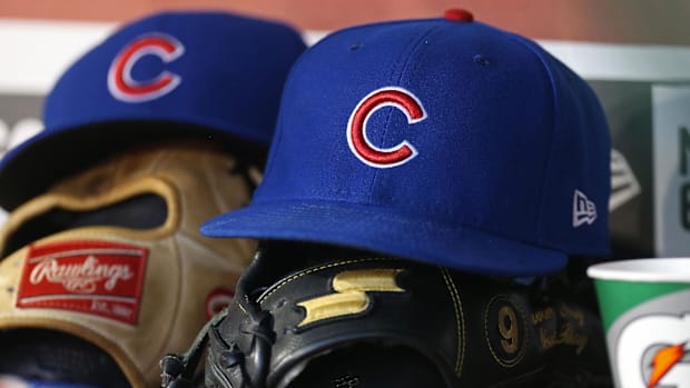 The cap and glove of Chicago Cubs players sit on the back rail of a dugout during a game The cap and glove of Chicago Cubs players sit on the back rail of a dugout during a game