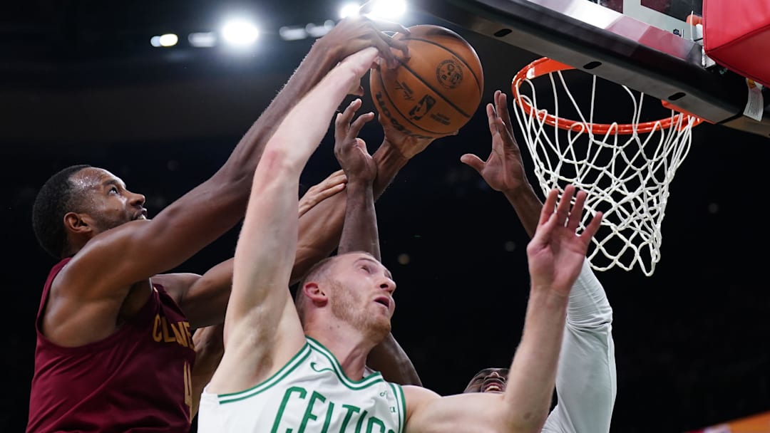 Oct 29, 2025; Boston, Massachusetts, USA; Cleveland Cavaliers center Evan Mobley (4) works for the ball against Boston Celtics forward Sam Hauser (30) and guard/forward Jaylen Brown (7) in the second half at TD Garden. Mandatory Credit: David Butler II-Imagn Images