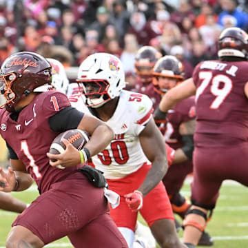 Nov 1, 2025; Blacksburg, Virginia, USA; Virginia Tech Hokies quarterback Kyron Drones (1) runs the ball as Louisville Cardinals defensive lineman Clev Lubin (50) defends during the third quarter at Lane Stadium. Mandatory Credit: Brian Bishop-Imagn Images
