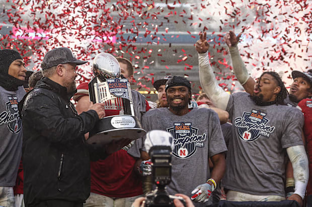 Nebraska Cornhuskers head coach Matt Rhule holds the championship trophy as Cornhuskers players celebrate after the game.
