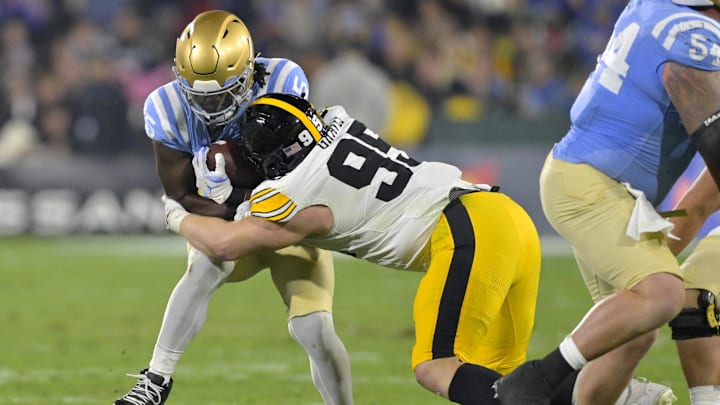 Nov 8, 2024; Pasadena, California, USA;   UCLA Bruins running back T.J. Harden (25) is stopped by Iowa Hawkeyes defensive lineman Aaron Graves (95) after a first down in the first half at the Rose Bowl. Mandatory Credit: Jayne Kamin-Oncea-Imagn Images