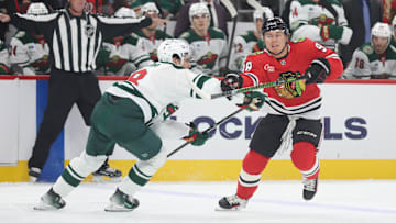 Oct 3, 2025; Chicago, Illinois, USA; Chicago Blackhawks center Connor Bedard (98) and Minnesota Wild defenseman Zeev Buium (8) battle for control of the puck during the first period at United Center. Mandatory Credit: Talia Sprague-Imagn Images