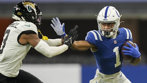 Colts receiver Josh Downs (blue jersey) pushes away a defender from trying to tackle him.