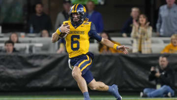 Dec 27, 2023; Charlotte, NC, USA; West Virginia Mountaineers quarterback Garrett Greene (6) runs the ball against the North Carolina Tar Heels during the first half at Bank of America Stadium. Mandatory Credit: Jim Dedmon-USA TODAY Sports
