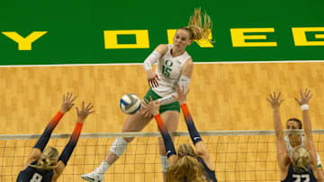 Oregon’s Mimi Colyer, center, goes up for a shot against Illinois during the first set at Matthew Knight Arena Sept. 27, 2024.