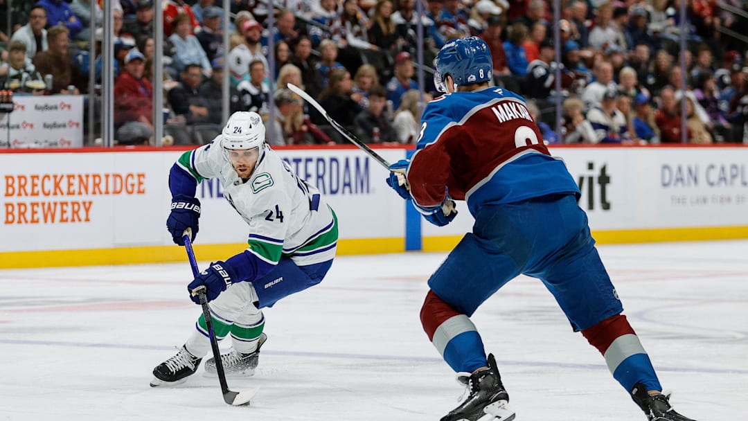 Apr 10, 2025; Denver, Colorado, USA; Vancouver Canucks center Pius Suter (24) controls the puck as Colorado Avalanche defenseman Cale Makar (8) defends in the first period at Ball Arena. Mandatory Credit: Isaiah J. Downing-Imagn Images