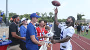 Bills running back James Cook throws a football back to a fan in the stands after autographing the ball during the opening day of Buffalo Bills training camp.