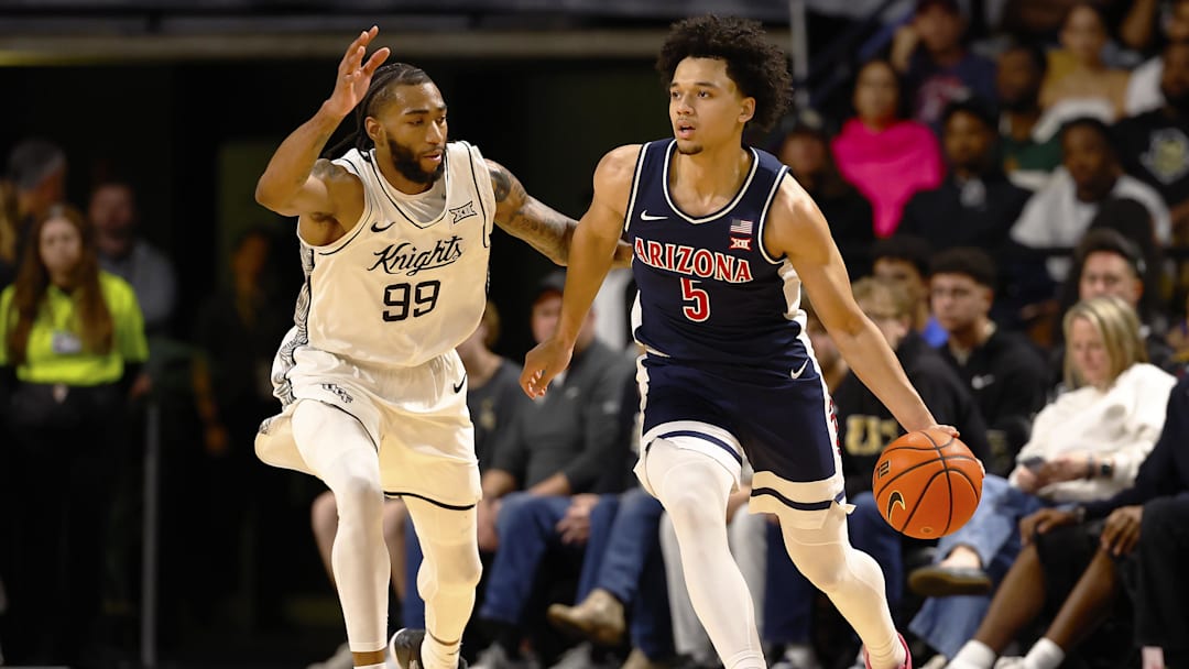 Jan 17, 2026; Orlando, Florida, USA;  Arizona Wildcats guard Brayden Burries (5) dribbles around Central Florida Knights forward Jordan Burks (99) in the first half at Addition Financial Arena. Mandatory Credit: Russell Lansford-Imagn Images