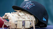 Apr 24, 2024; Atlanta, Georgia, USA; A detailed view of a Miami Marlins hat and glove in the dugout before a game against the Atlanta Braves at Truist Park. 