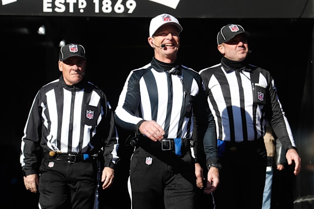 NFL back judge Brad Freeman (left) and referee Land Clark (white hat) and umpire Paul King (right) take the field before the 