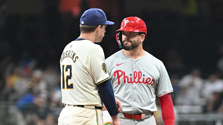 Sep 16, 2024; Milwaukee, Wisconsin, USA; Milwaukee Brewers first baseman Rhys Hoskins (12) and Philadelphia Phillies designated hitter Kyle Schwarber (12) talk to each other during a pitching change in the sixth inning at American Family Field.