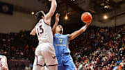 Mar 4, 2025; Blacksburg, Virginia, USA; North Carolina Tar Heels guard Seth Trimble (7) goes up for a layup as Virginia Tech Hokies forward Ben Burnham (13) defends during the second half at Cassell Coliseum. Mandatory Credit: Brian Bishop-Imagn Images