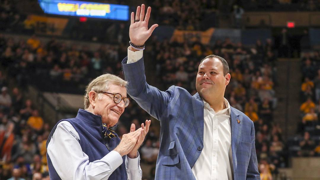 Dec 18, 2022; Morgantown, West Virginia, USA; West Virginia University President Gordon Gee welcomes new West Virginia Mountaineers Athletic Director Wren Baker during the first half against the Buffalo Bulls at WVU Coliseum. Mandatory Credit: Ben Queen-Imagn Images