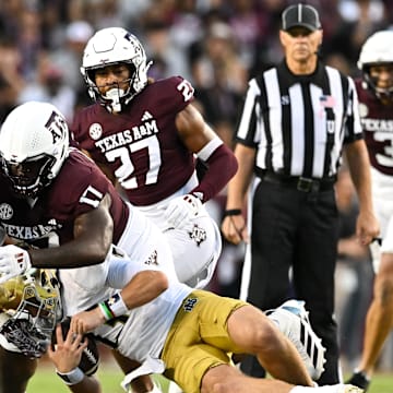 Aug 31, 2024; College Station, Texas, USA;  Texas A&M Aggies linebacker Taurean York (21) and defensive lineman Albert Regis (17) tackle Notre Dame Fighting Irish quarterback Riley Leonard (13) during the second quarter at Kyle Field. Mandatory Credit: Maria Lysaker-Imagn Images