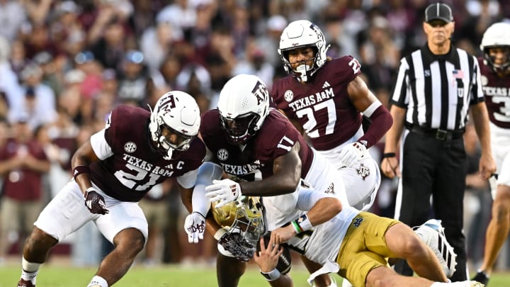 Aug 31, 2024; College Station, Texas, USA;  Texas A&M Aggies linebacker Taurean York (21) and defensive lineman Albert Regis (17) tackle Notre Dame Fighting Irish quarterback Riley Leonard (13) during the second quarter at Kyle Field. Mandatory Credit: Maria Lysaker-USA TODAY Sports